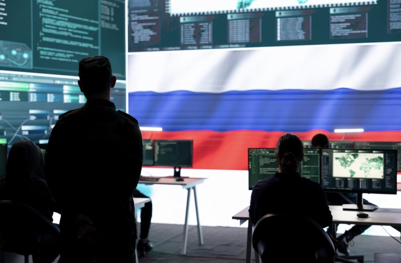 Operators in a control room with a Russian flag on the screen
