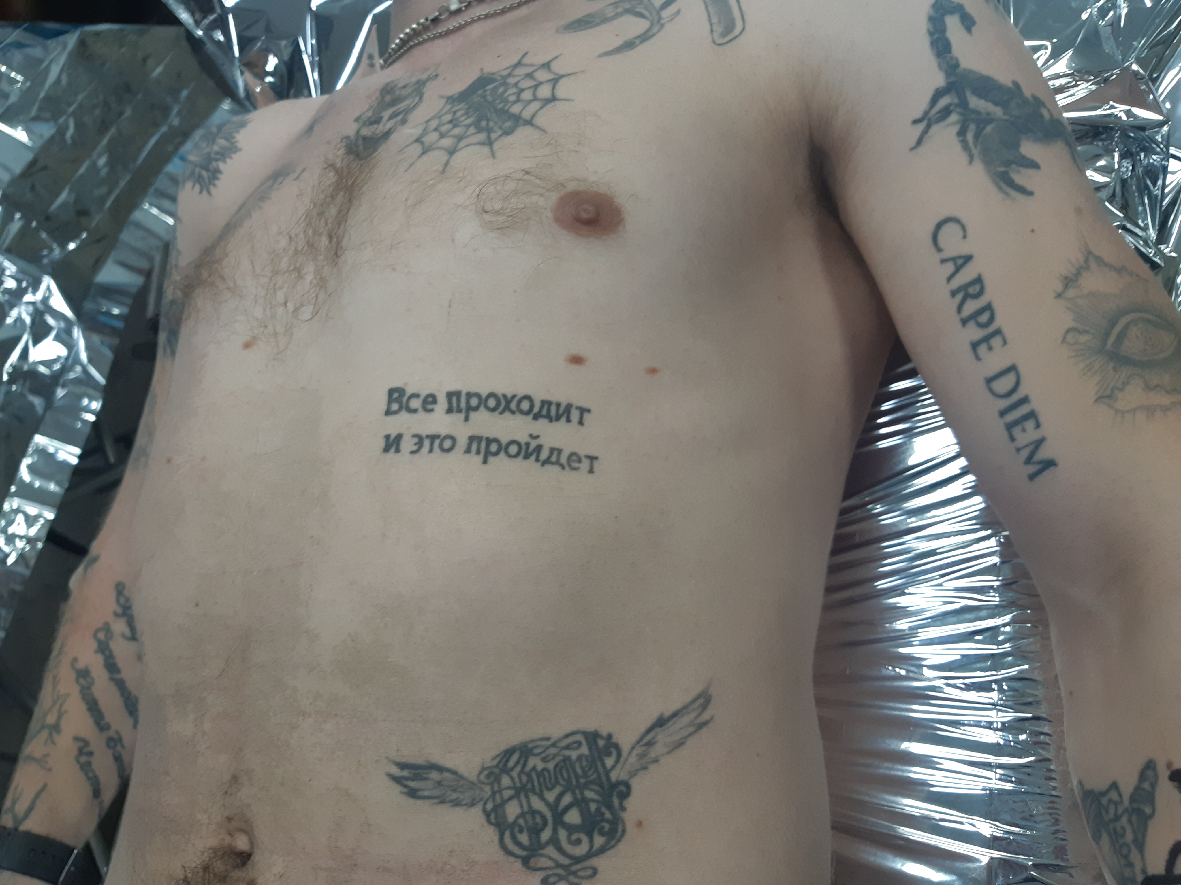 Tattooed torso with the phrase 'This too shall pass'
