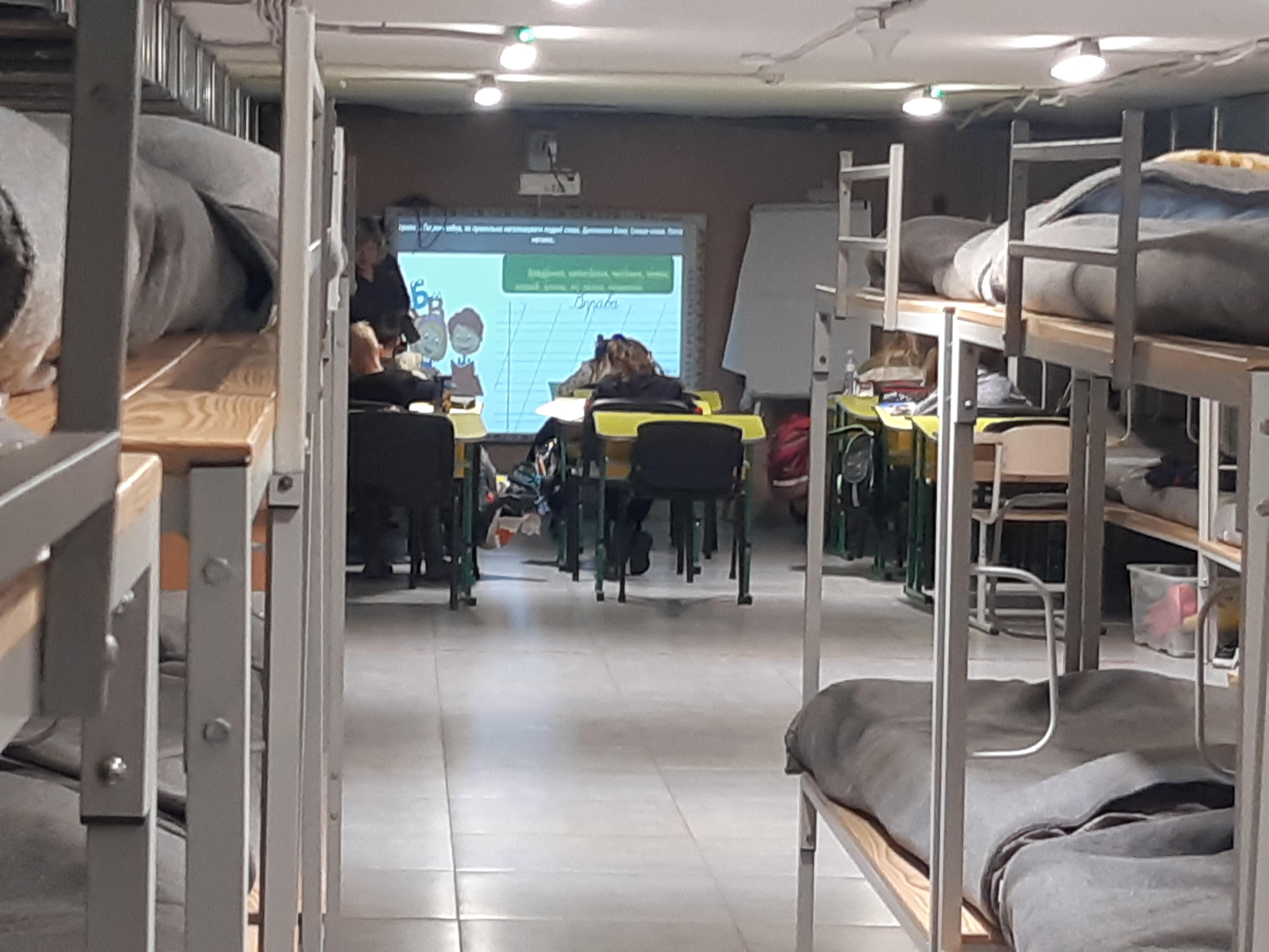 Children attend a lesson at desks in an underground shelter fitted with metal bunk beds in Ukraine